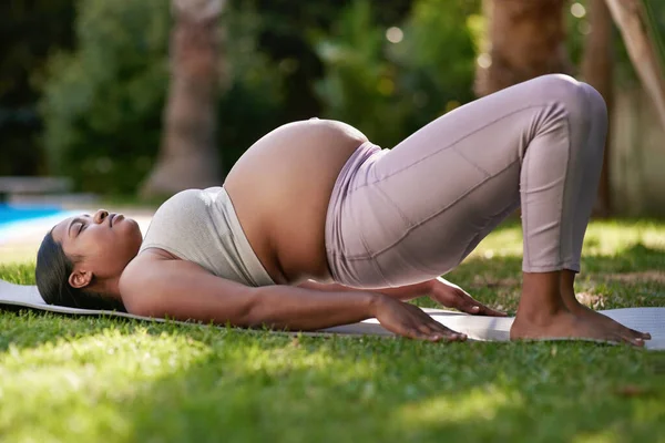 Esercizi a basso impatto sono grandi per le donne nel loro terzo trimestre. Colpo di una donna incinta che fa yoga fuori. — Foto Stock