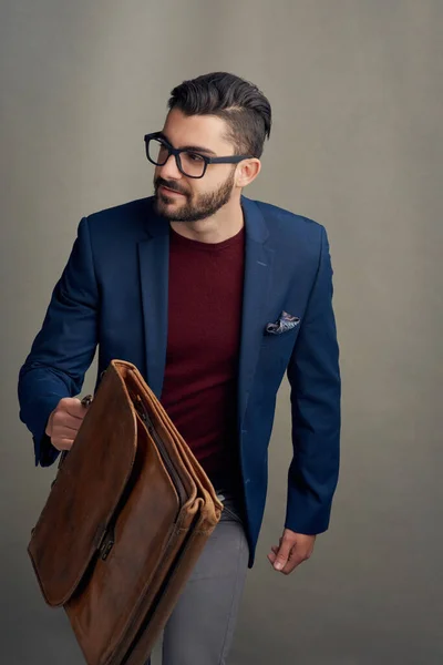 Donde quiera que vayas, ve con estilo. Estudio de un joven guapo llevando una bolsa sobre un fondo gris. —  Fotos de Stock