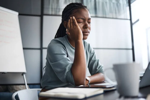 Devia tomar um analgésico por isto. Tiro de uma jovem empresária olhando estressado enquanto trabalhava em um laptop em um escritório. — Fotografia de Stock