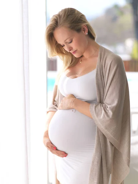 Zoveel genegenheid voor haar broodje in de oven. Gehakt schot van een aantrekkelijke jonge zwangere vrouw die haar buik terwijl staan in haar huis. — Stockfoto