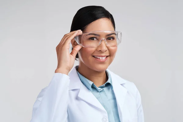 Ready to get to work. Cropped portrait of an attractive young female scientist wearing goggles in studio against a grey background. — Stock Photo, Image