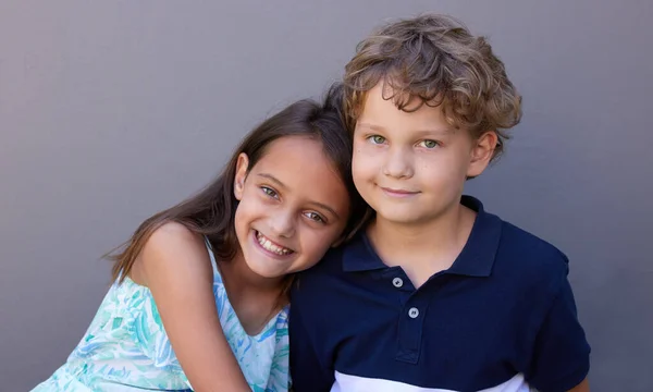 Bueno, sean mejores amigos de por vida. Foto de un niño y una niña sentados juntos sobre un fondo gris. —  Fotos de Stock
