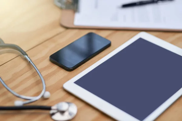 Lekarze na co dzień. Zbliżenie tabletu, smartfona, schowka i stetoskopu na biurku lekarza. — Zdjęcie stockowe