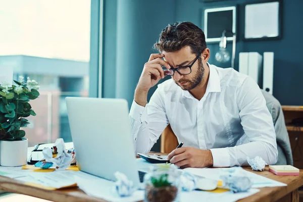 Zijn werk begint hem serieus te stressen. Shot van een jonge zakenman op zoek gestresst tijdens het werken op een laptop in een kantoor. — Stockfoto