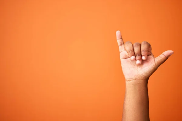 La vida es genial. Fotografía de una persona irreconocible mostrando un signo de shaka sobre un fondo naranja. — Foto de Stock