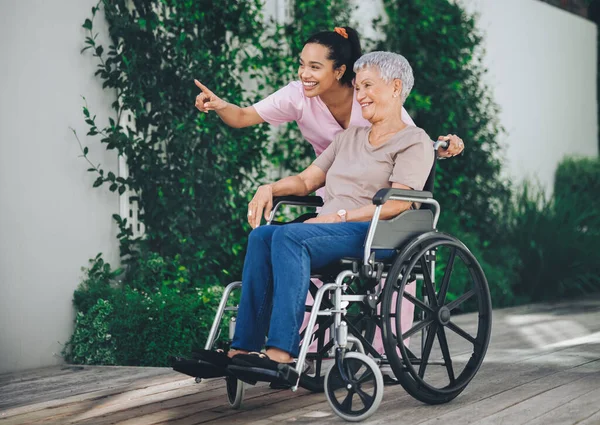 Um corpo mais velho para um espírito intemporal. Tiro de uma jovem enfermeira cuidando de uma mulher mais velha em uma cadeira de rodas. — Fotografia de Stock