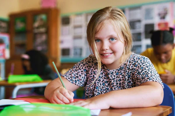 Ich bin immer wissbegierig. Aufnahme eines jungen Mädchens, das in der Schule in ihrem Klassenzimmer sitzt und in ihr Arbeitsbuch schreibt. — Stockfoto