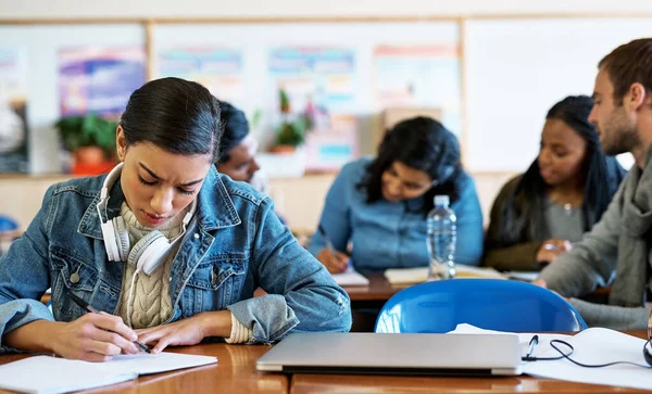 Os estudos dela vêm primeiro. Tiro recortado de um jovem estudante universitário atraente tomando notas na aula. — Fotografia de Stock