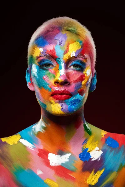 색을 더 하는 것은 모든 차이를 만듭니다. 스튜디오에서는 얼굴에 다양 한 색깔의 페인트칠을 한 젊은 여성 이 포즈를 취하는 모습을 찍었다. — 스톡 사진