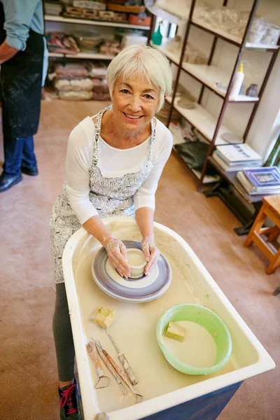 Aprender una nueva habilidad es muy divertido. Tiro de una mujer mayor haciendo una olla de cerámica en un taller. — Foto de Stock