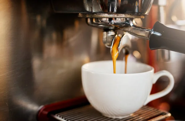 Nog eentje, dank je. Close-up shot van een espresso maker gieten koffie in een kopje in een cafe. — Stockfoto