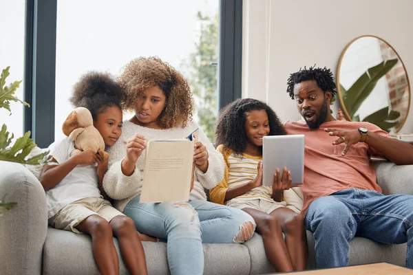 Leren kan op twee verschillende manieren gebeuren. Foto van een jong gezin dat samen tijd doorbrengt en thuis een digitale tablet gebruikt. — Stockfoto