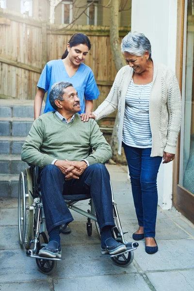 Onde estarei sem ti na minha vida? Tiro de um idoso alegre sentado em uma cadeira de rodas, sendo apoiado por sua esposa e uma enfermeira em casa durante o dia. — Fotografia de Stock