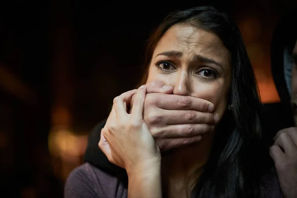 Försvarslösa och i fara. Porträtt av en rädd ung kvinna med sina angripare handen över munnen. — Stockfoto