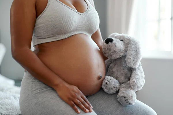 Ani Teddy se nemůže dočkat, až si bude hrát s dítětem. Detailní záběr na nepoznatelnou ženu držící plyšového medvídka v blízkosti jejího těhotného břicha doma. — Stock fotografie