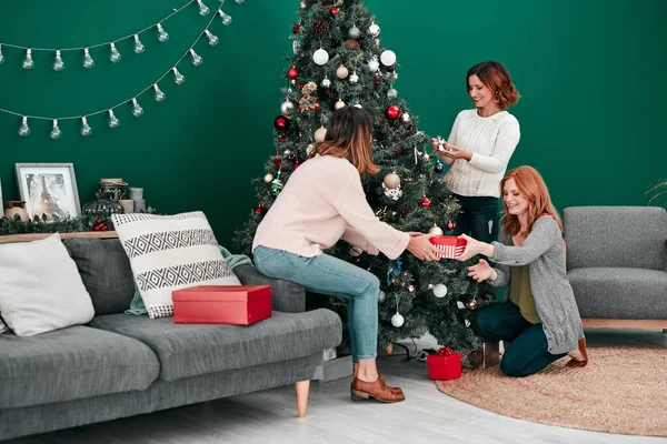 Acérquense. Tiro de tres atractivas mujeres decorando un árbol de Navidad juntas en casa. — Foto de Stock