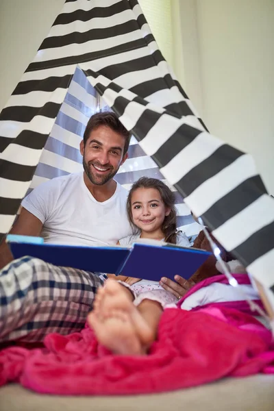 Não há nada mais importante do que tempo de qualidade juntos. Retrato de um pai lendo um livro com sua filha em uma tenda em casa. — Fotografia de Stock