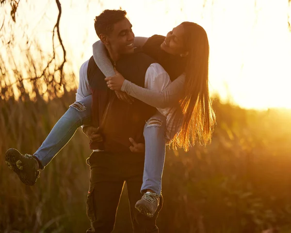 Tens-te tornado tão forte ultimamente. Tiro de um jovem dando a sua namorada um passeio de piggyback. — Fotografia de Stock