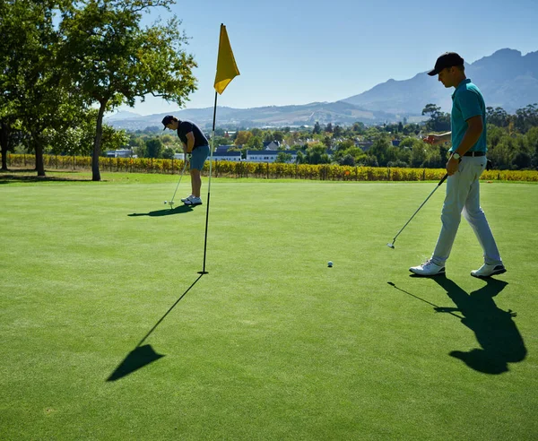 J'ai mis toute la journée. Tourné de deux jeunes hommes concentrés jouant à un jeu de golf à l'extérieur sur un terrain de golf. — Photo