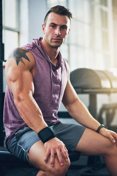 Chodzi o utrzymanie dyscypliny. Portret muskularnego młodzieńca siedzącego na siłowni. — Zdjęcie stockowe