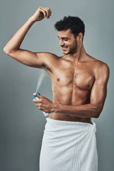 Niemand heeft tijd voor lichaamsgeur. Studio shot van een knappe jongeman aanbrengen deodorant tegen een grijze achtergrond. — Stockfoto
