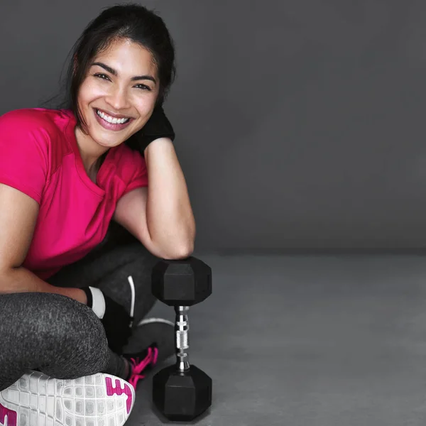 Enjoying every workout. Studio shot of an attractive young woman working out with dumbbells against a gray background. — Stock Photo, Image