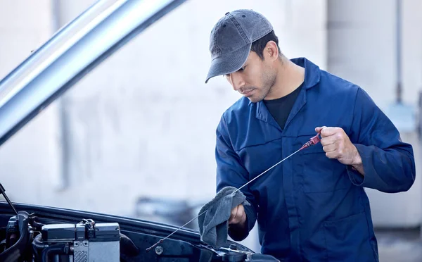 La lubricación es importante para todos los motores. Recortado disparo de un joven mecánico guapo trabajando en el motor de un coche durante un servicio. —  Fotos de Stock