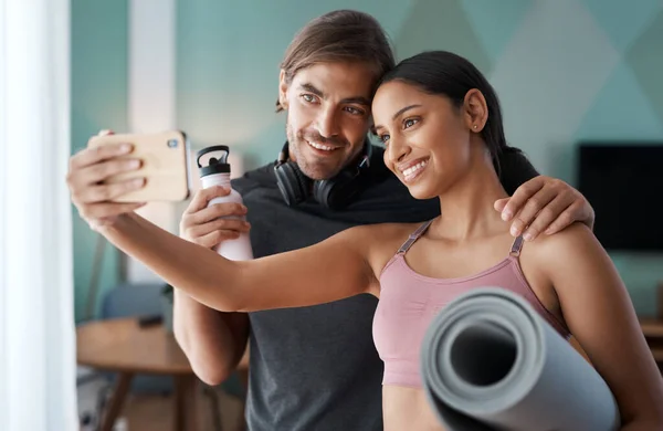 Aggiornamento dello stato Allenamento completato. Colpo ritagliato di una giovane coppia atletica scattare selfie prima di iniziare il loro allenamento a casa. — Foto Stock