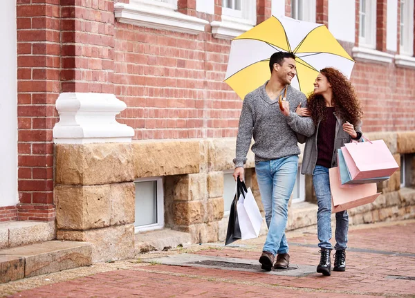 Un po 'di pioggia non fermerà la loro corsa allo shopping. Colpo di scena completo di una giovane coppia affettuosa che si diverte a fare shopping in città. — Foto Stock