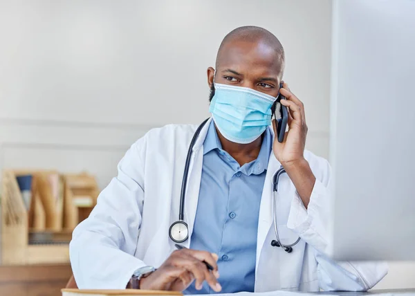 Puo 'ascoltare i tuoi bisogni di salute. Girato di un giovane medico su una chiamata mentre scriveva in un quaderno al lavoro. — Foto Stock