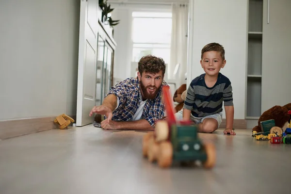 ¿Qué pasa con los chicos y los coches. Tiro de un joven guapo y su hijo jugando con juguetes en el piso del dormitorio. — Foto de Stock