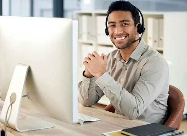 Dag en nacht houden we onze klantenservice strak. Portret van een jonge zakenman met een headset en computer in een modern kantoor. — Stockfoto