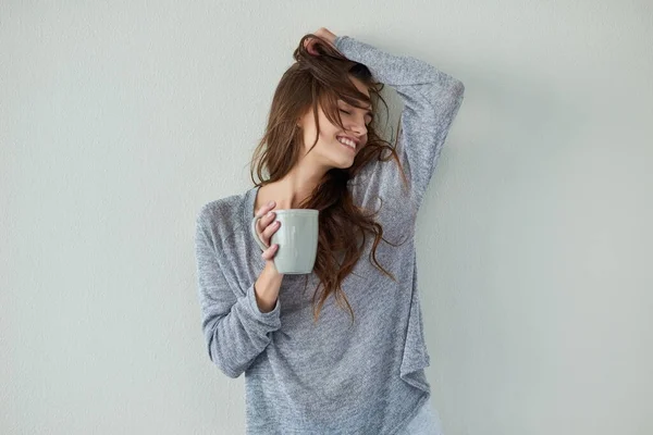 Ich bin heute in einer unbeschwerten Art von Stimmung. Studioaufnahme einer attraktiven jungen Frau mit erhobenem Arm beim Kaffeetrinken vor weißem Hintergrund. — Stockfoto