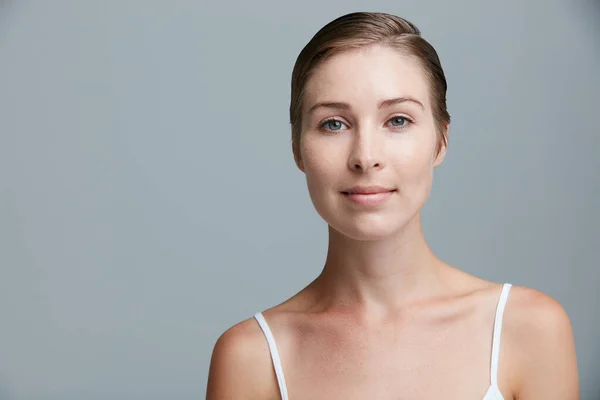 Weniger Make-up, mehr ich. Studioporträt einer attraktiven jungen Frau, die vor grauem Hintergrund posiert. — Stockfoto