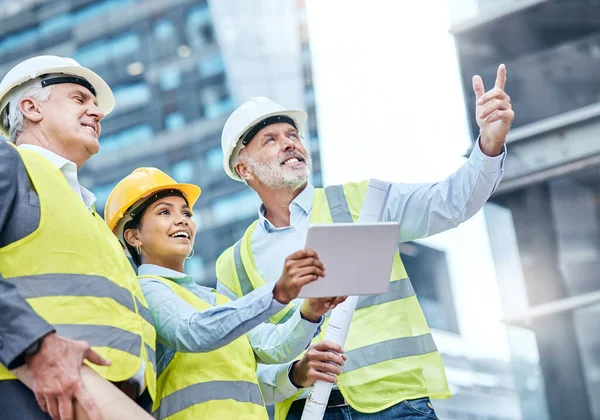 Gérer ensemble un projet complexe. Prise de vue d'un groupe d'hommes d'affaires utilisant une tablette numérique pendant qu'ils travaillent sur un chantier de construction. — Photo