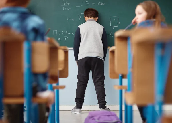 Moeilijkheden op school. Achteraanzicht foto van een basisschooljongen met zijn hoofd op het schoolbord in de klas. — Stockfoto