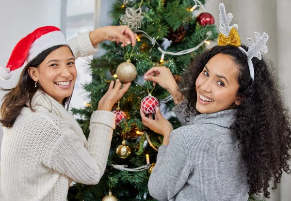 Ağacı süsleme zamanı. Evde Noel ağacını süsleyen iki genç kadının fotoğrafı.. — Stok fotoğraf