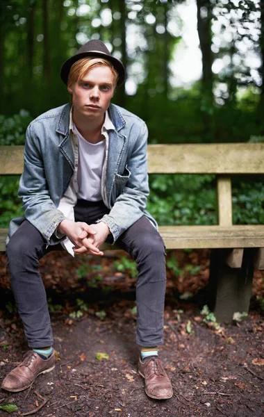 Att komma bort från allt. Porträtt av en stilig och stilig ung man som sitter på en bänk i en skog. — Stockfoto