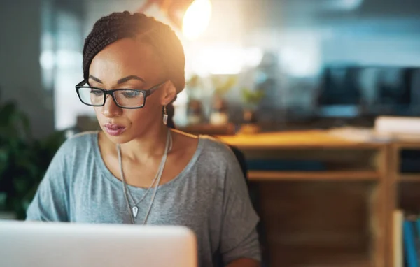 Maximaler Aufwand. Schnappschuss einer jungen Frau, die ihren Laptop benutzt, während sie spät in ihrem Büro arbeitet. — Stockfoto