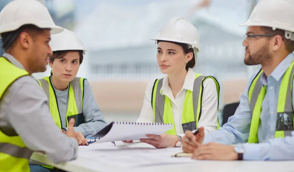 Er zijn regels waaraan we ons moeten houden. Gesneden foto van een groep jonge bouwvakkers die tijdens een vergadering rond de bestuurstafel zitten. — Stockfoto