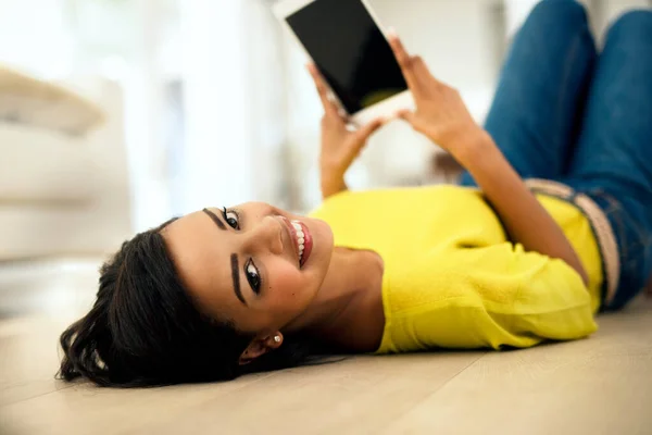 Mina nya tabletter är jättebra. Skjuten av en ung kvinna som använder en digital tablett när hon ligger på golvet hemma. — Stockfoto