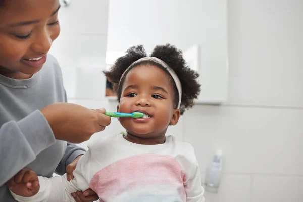 Máma jí pomůže udržet její dětské zuby čisté. Zastřelen matka kartáčování její malé dcery zuby v koupelně doma. — Stock fotografie
