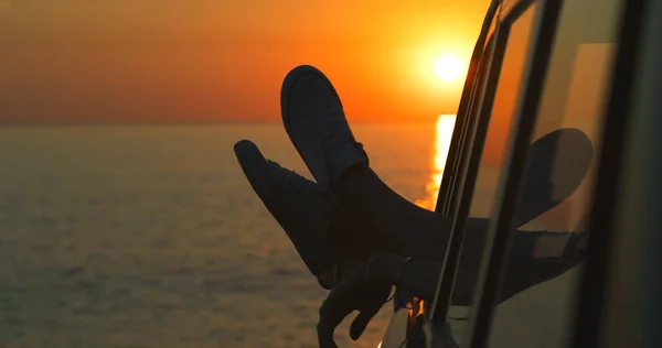 Bacaklarını tut ve sakinleş. Tanımlanamayan bir kadının sahildeki bir arabanın camından sarkan bacakları.. — Stok fotoğraf