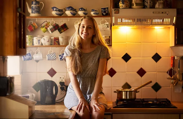 Para casa no fim-de-semana. Retrato de uma jovem mulher atraente sentada em sua cozinha. — Fotografia de Stock