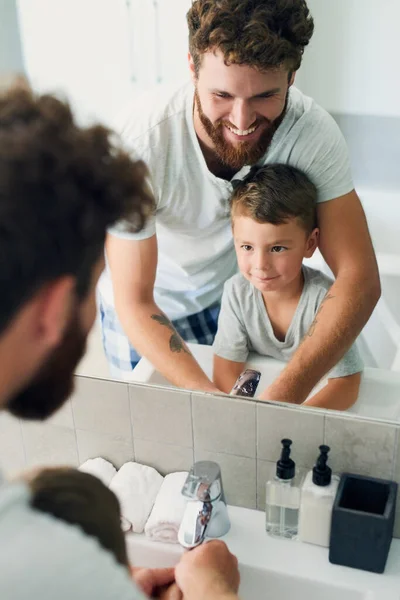 Antes de fazer alguma coisa, certifique-se de que as suas mãos estão limpas. Tiro cortado de um jovem pai bonito ajudando seu adorável menino lavar as mãos no banheiro em casa. — Fotografia de Stock