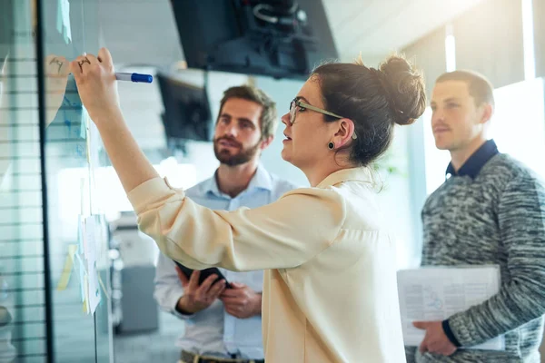 Tutto diventa più chiaro una volta che si enigma attraverso di essa. Girato di un gruppo di uomini d'affari brainstorming con note su una parete di vetro in un ufficio. — Foto Stock