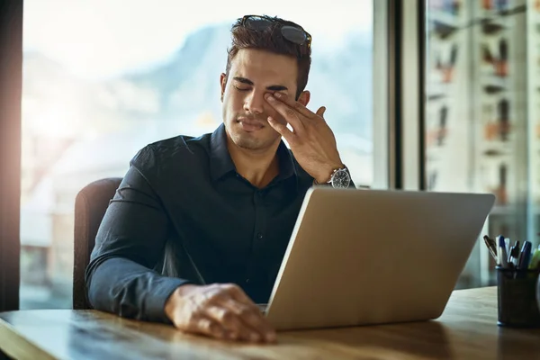 Dieser Tag fühlt sich an, als würde er nie enden. Aufnahme eines jungen Geschäftsmannes, der gestresst aussieht, während er in einem Büro an einem Laptop arbeitet. — Stockfoto