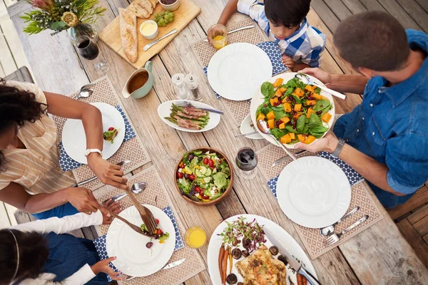 매 끼니 마다 사랑 과 행복을 바친다. 야외에서 식탁 주위에서 함께 식사를 즐기고 있는 네 식구의 어린 가족을 높은 각도로 찍은 사진. — 스톡 사진