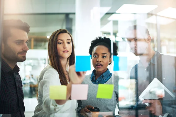 Sätt idéerna i fokus. Beskuren bild av medarbetare med klibbiga anteckningar på en glasvägg under ett möte. — Stockfoto