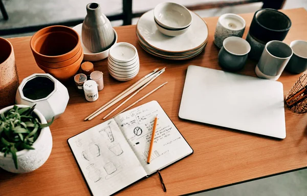 Un bureau plein d'espoir et de rêves. Plan grand angle d'un potier esquisse dans un carnet et son ordinateur portable sur un bureau dans son atelier. — Photo